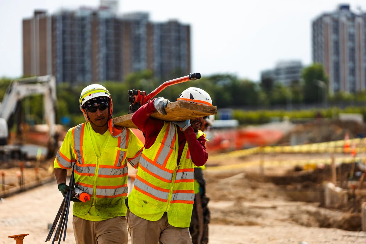 two pave america employees hauling a piece of lumber