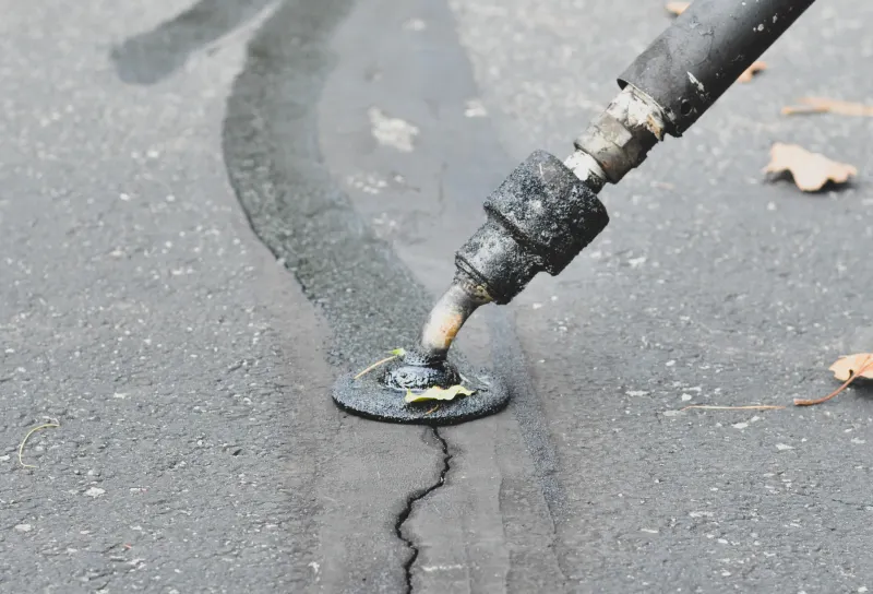 sanding the seal on a crack in the pavement