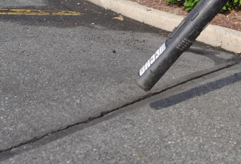air blower blowing into a crack in the pavement